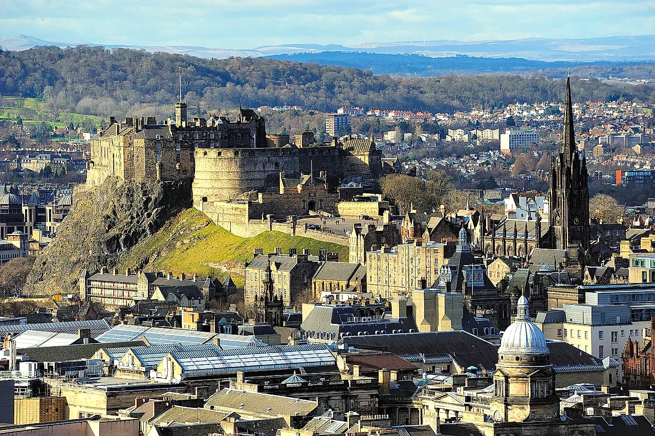 Edinburgh Castle on its rock above the Old Town rooftops, with the tall Gothic spire of a church rising beside it