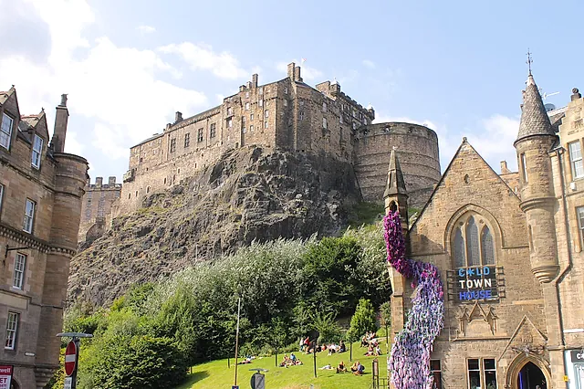 Edinburgh Castle on its crag seen from the Grassmarket, with Victorian stone buildings in the foreground and the castle walls rising behind