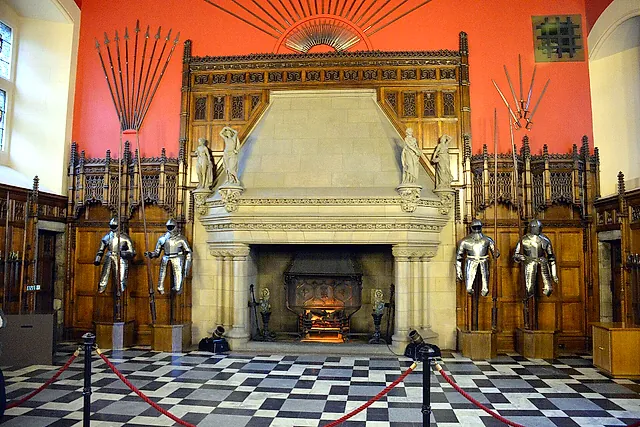 The Great Hall of Edinburgh Castle: the stone fireplace with suits of armour, spears fanned out on the red wall and the chequered floor