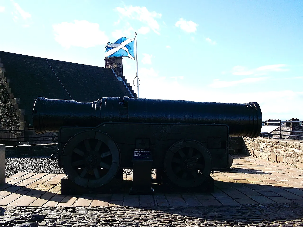 Mons Meg, the huge medieval siege cannon, on its carriage with stone cannonballs, with the Scottish saltire flying behind